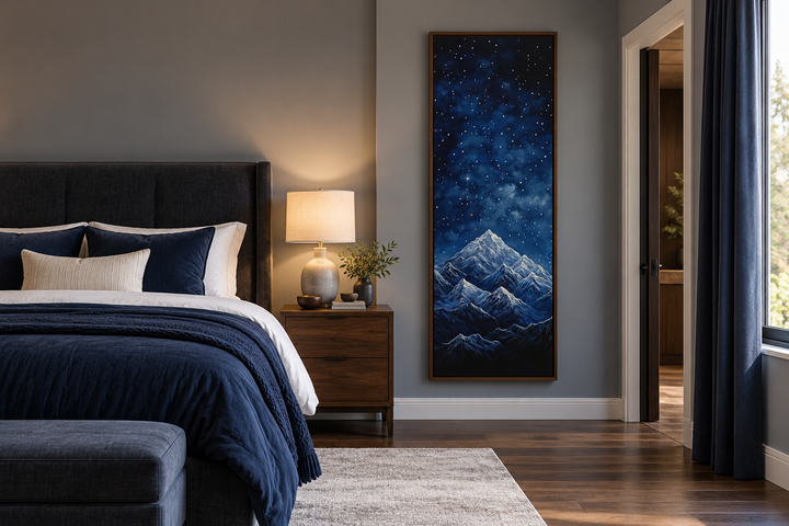 Tall narrow vertical framed canvas art of a navy blue starry night sky over snowy mountains.