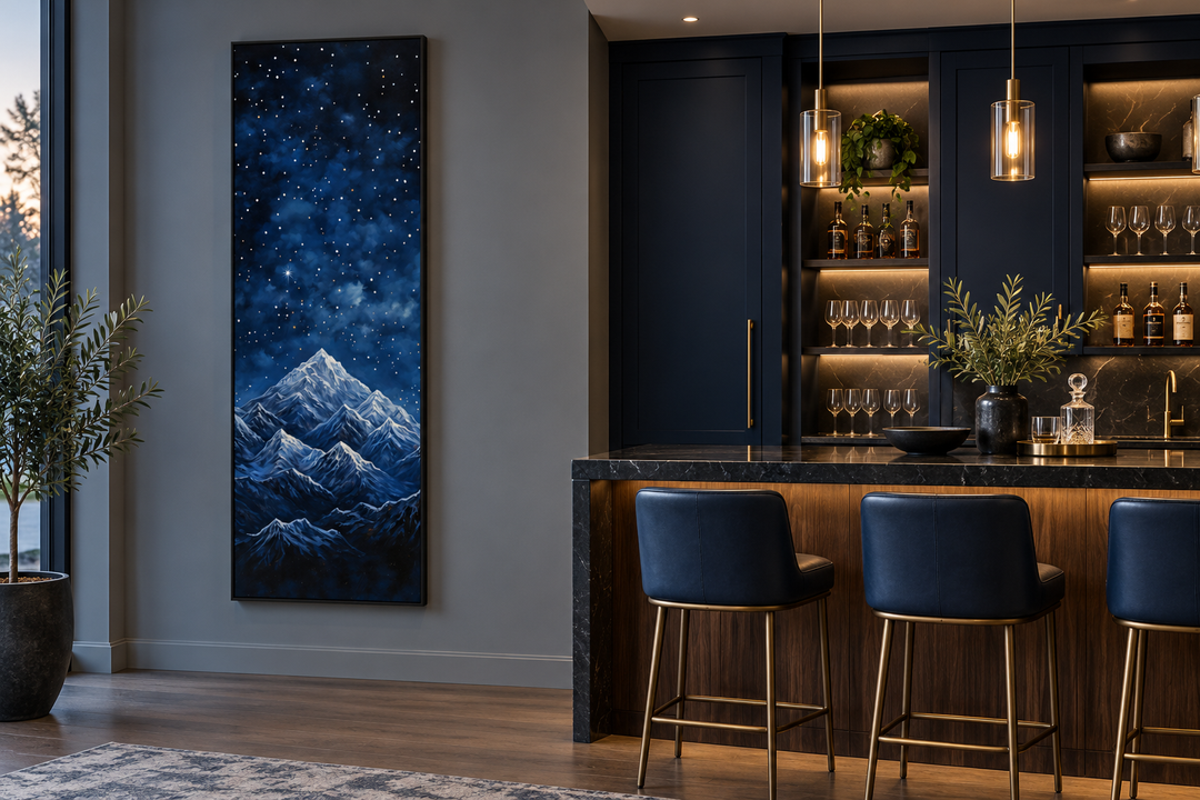 Tall narrow framed canvas art of a navy blue starry night sky over snow-capped mountains.