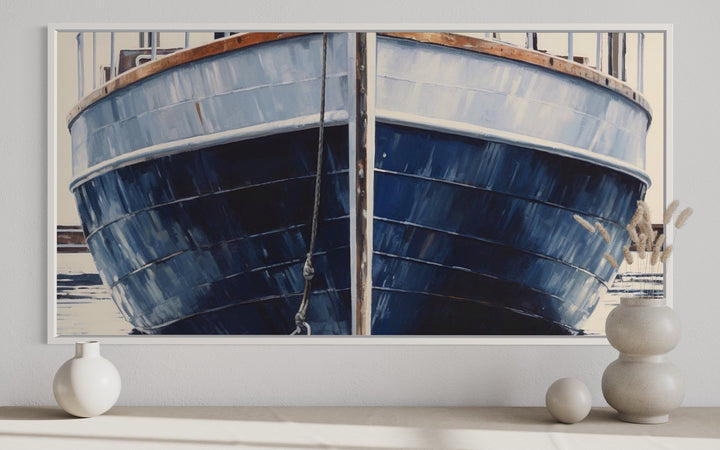 Close-up navy blue rustic boat painting in a white frame, displayed above a console table.