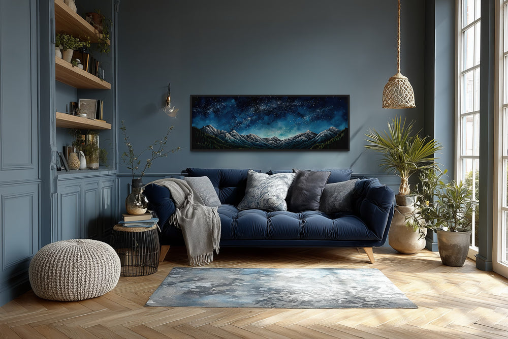 Horizontal framed canvas art of a navy blue starry night sky over mountains in a modern living room.