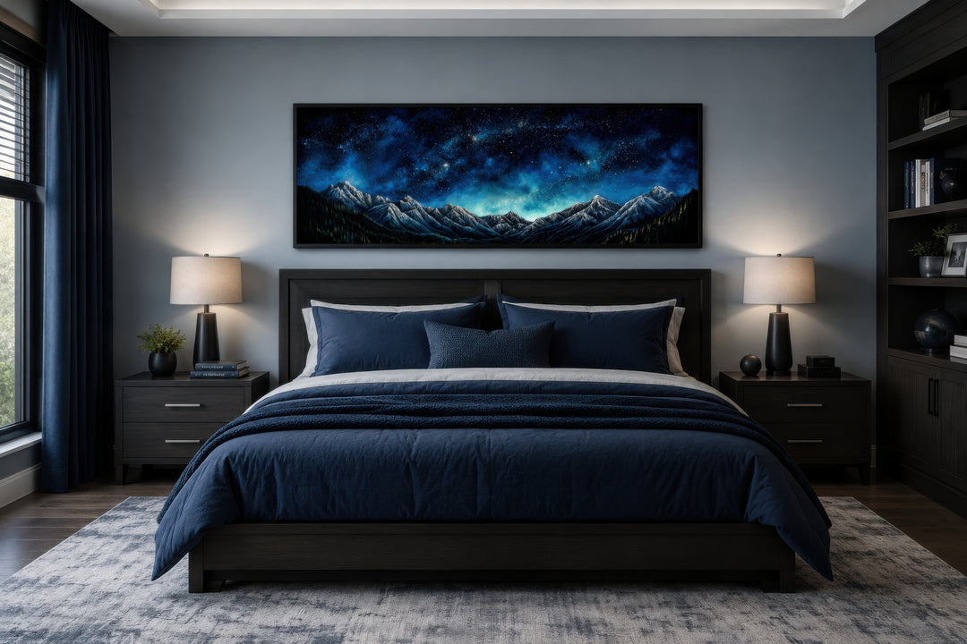 Navy blue starry night sky over mountains horizontal framed canvas wall art above a bed.