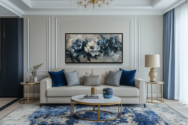 Navy blue and white abstract floral canvas wall art in a black frame above a beige sofa.