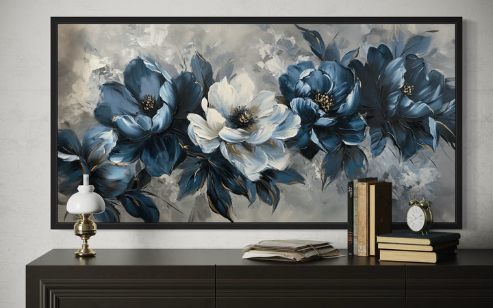Navy blue and white abstract floral canvas painting in a black frame above a dark wood console.