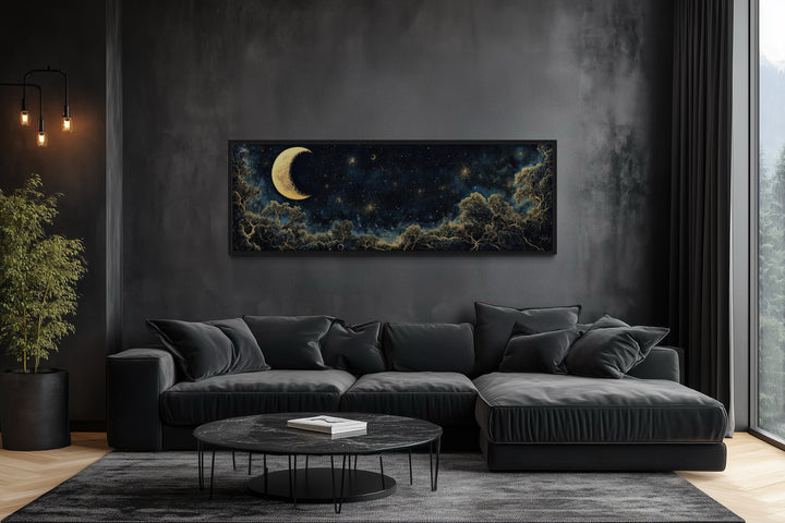 Navy blue and gold crescent moon and starry night sky horizontal wall art above a black sofa.