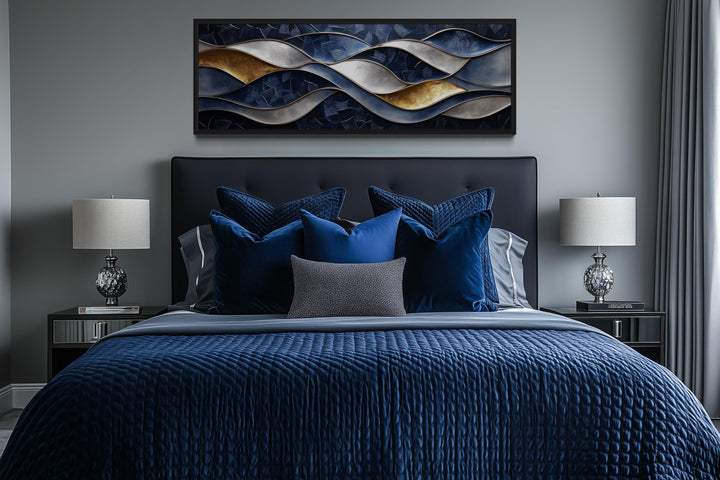 Navy and gold abstract wave horizontal wall art hanging above a bed with blue velvet pillows.
