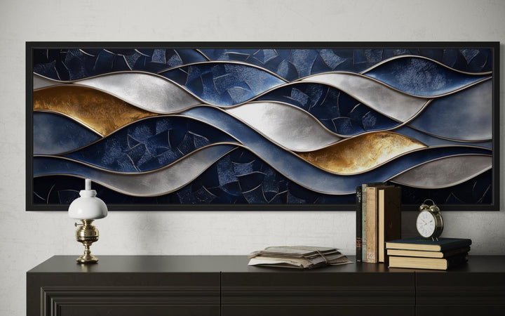 Navy and gold abstract wave horizontal wall art in a black frame above a dark wood console table.