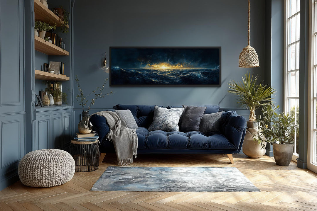 A panoramic navy and gold ocean sunset canvas hangs above a blue velvet sofa in a modern living room.