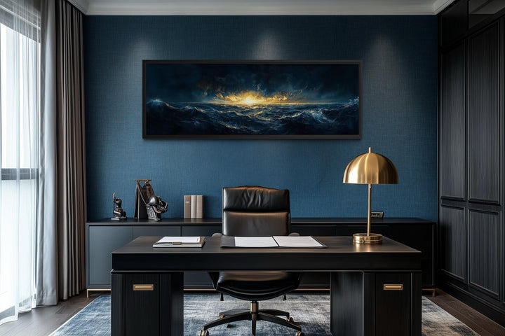 A panoramic navy and gold canvas of a stormy ocean sunset hangs in a modern, dark-toned office.