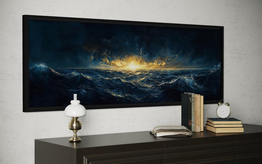 A wide horizontal canvas print of a navy and gold ocean sunset hangs above a dark wooden dresser.