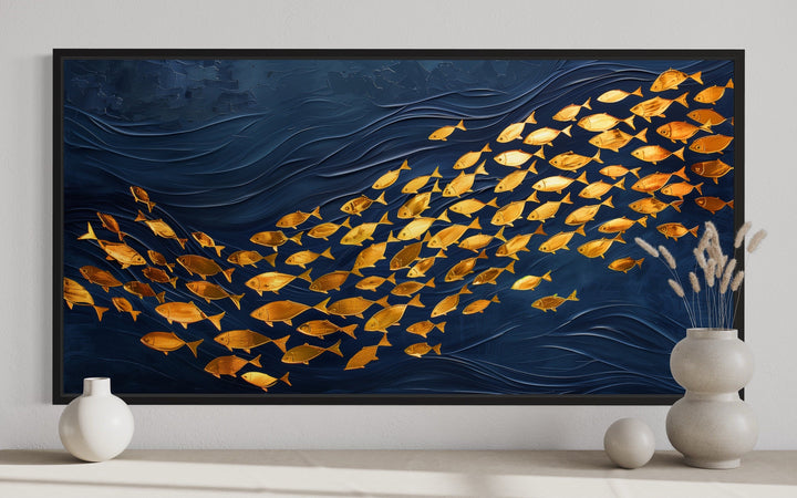 Framed navy blue canvas wall art featuring a school of shimmering gold fish in a wave pattern.
