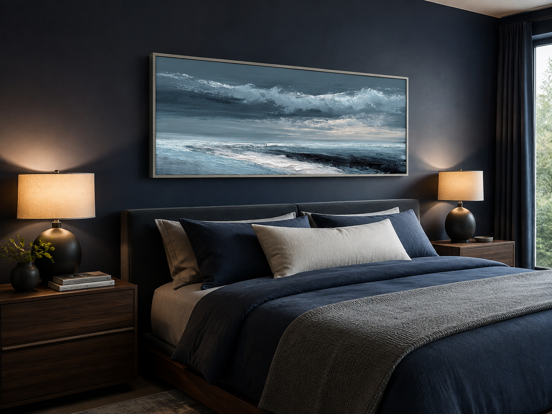 Navy blue and grey abstract ocean wall art in a long horizontal frame above a bed.