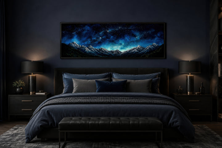 Navy blue starry night sky over mountains horizontal framed canvas wall art above a bed.