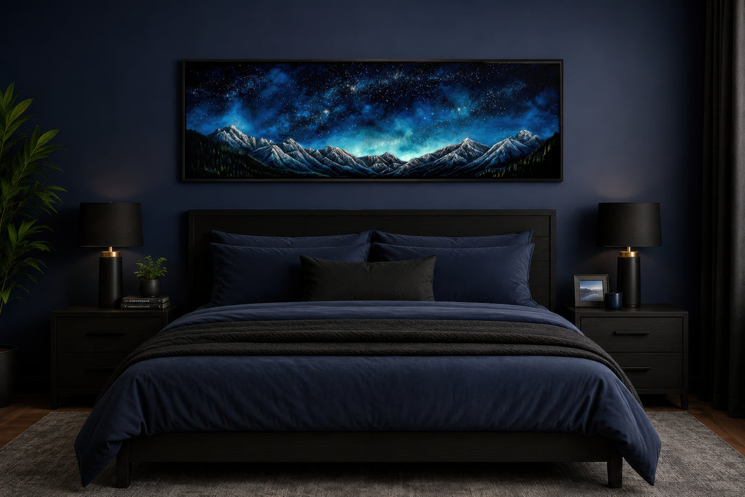 Navy blue starry night sky over mountains horizontal framed canvas wall art above a bed.