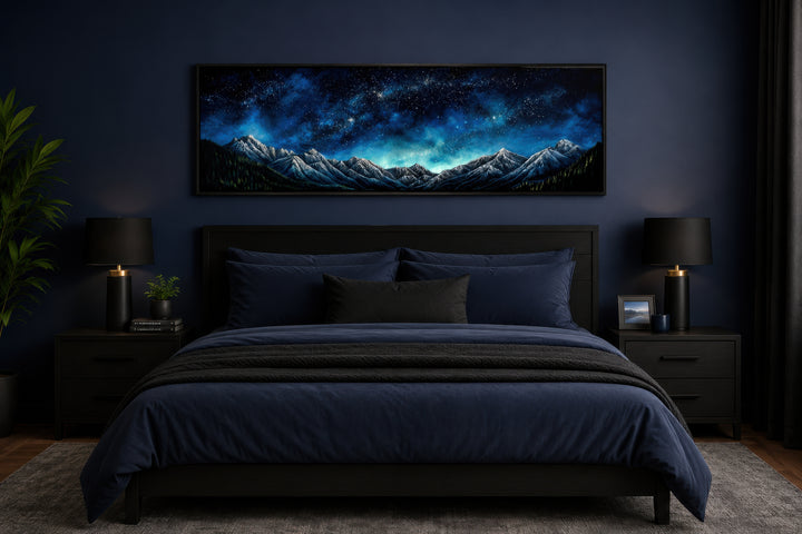 Navy blue starry night sky over mountains horizontal framed canvas wall art above a bed.