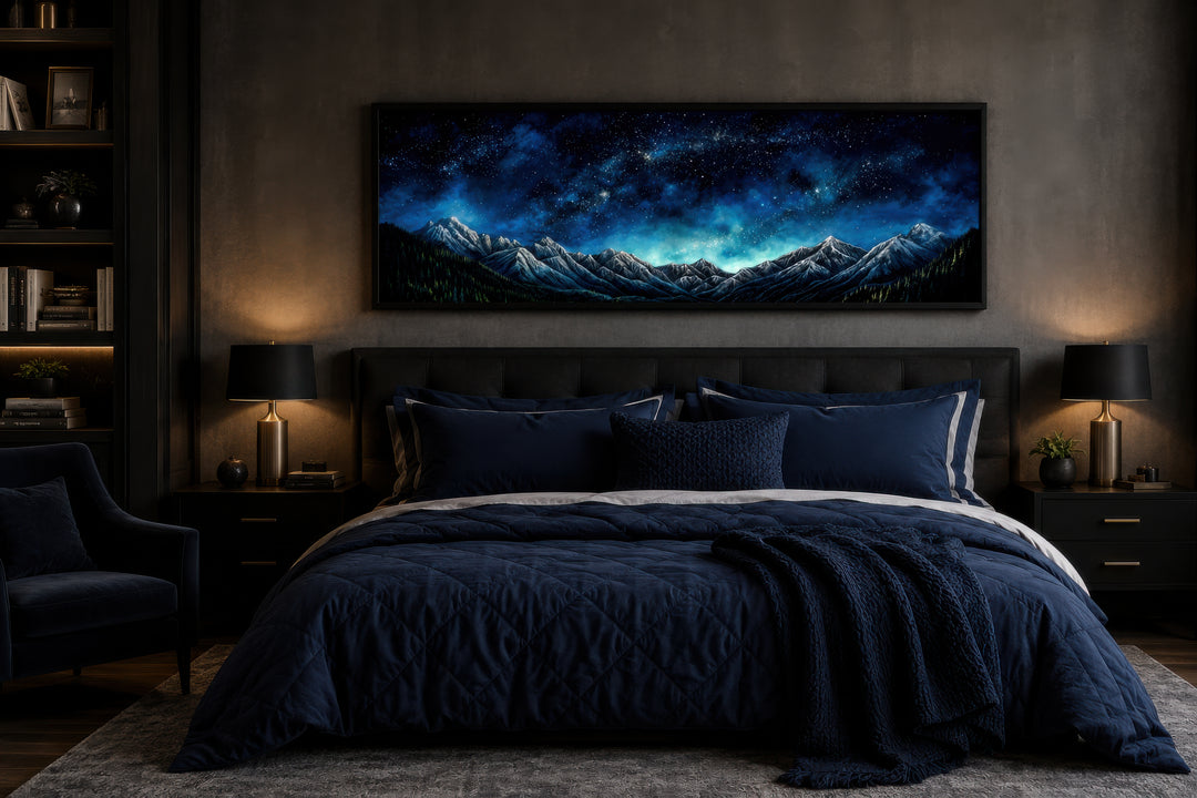 Navy blue starry night sky over mountains horizontal framed canvas wall art above a bed.