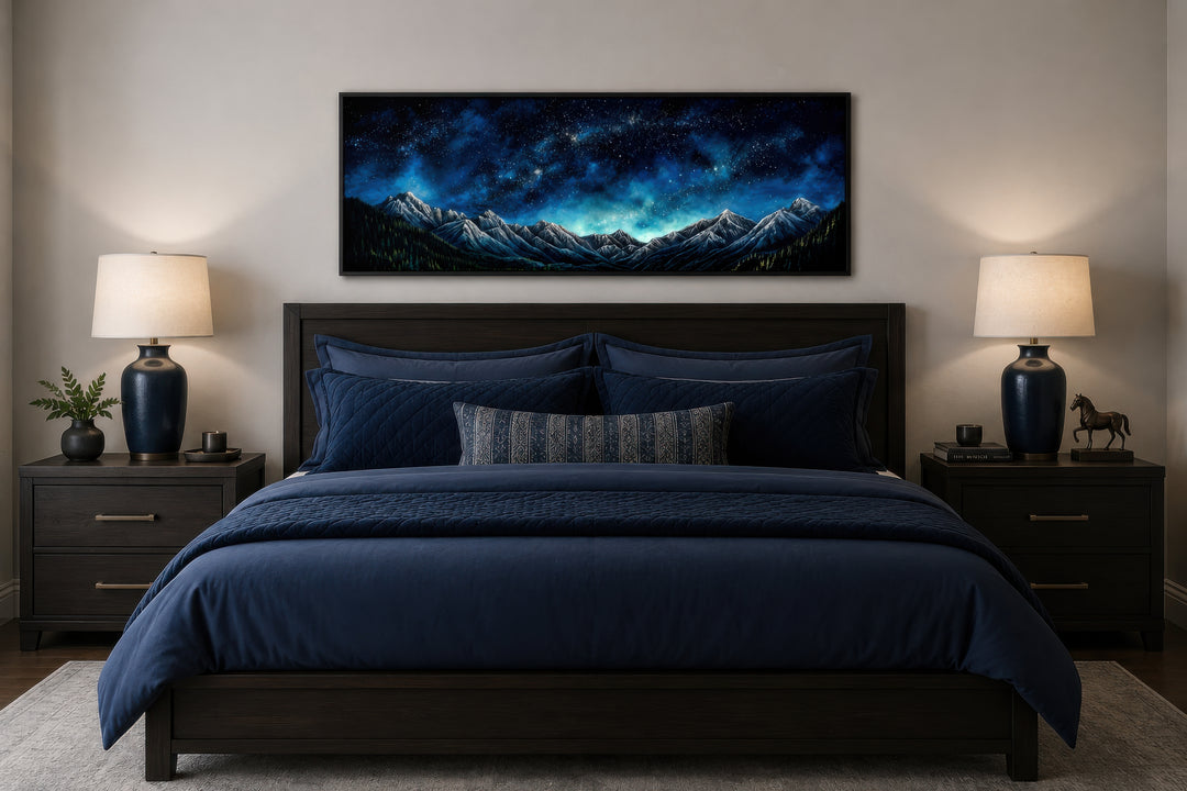 Navy blue starry night sky over mountains horizontal framed canvas wall art above a bed.