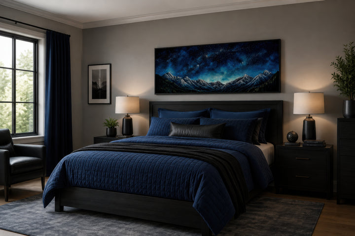 Navy blue starry night sky over mountains horizontal framed canvas wall art above a bed.