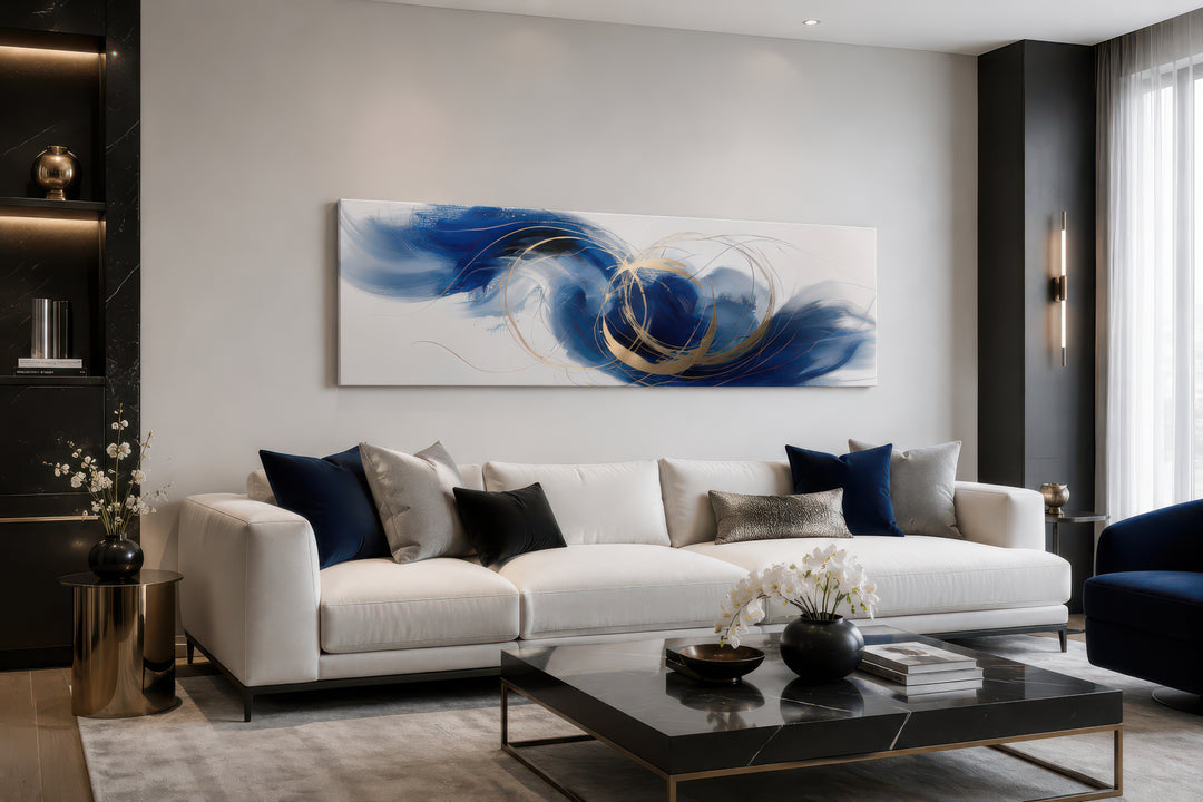 Blue, white, and gold minimalist abstract narrow horizontal wall art hanging above a white sofa.