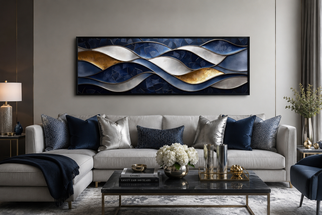 Navy and gold abstract wave horizontal wall art above a grey sofa with blue and silver pillows.