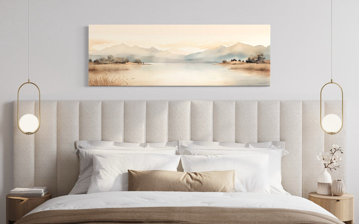 Neutral beige mountains lake long narrow framed canvas wall art hanging above a modern bed.
