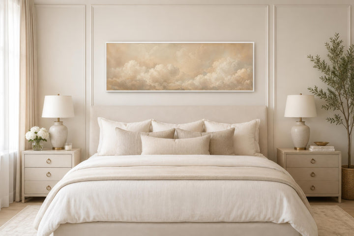 Long narrow horizontal canvas art of beige and white clouds hanging above a bed in a neutral room.