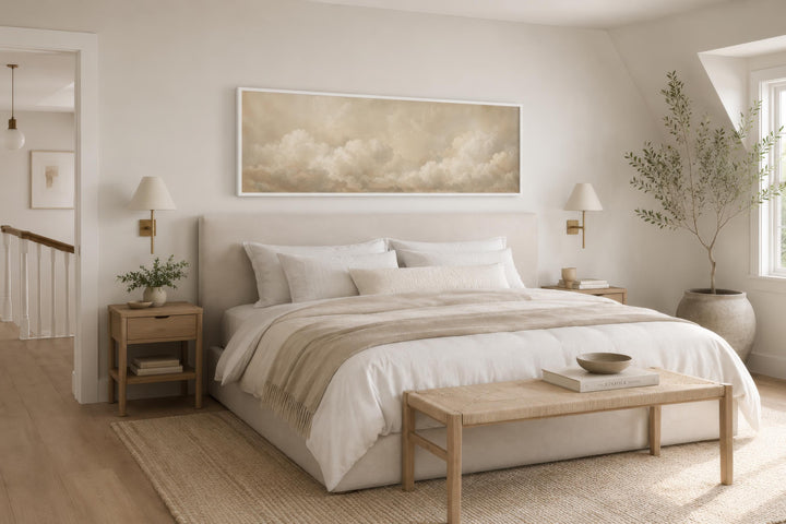 Long narrow horizontal canvas art of beige and white clouds hanging above a bed in a neutral room.