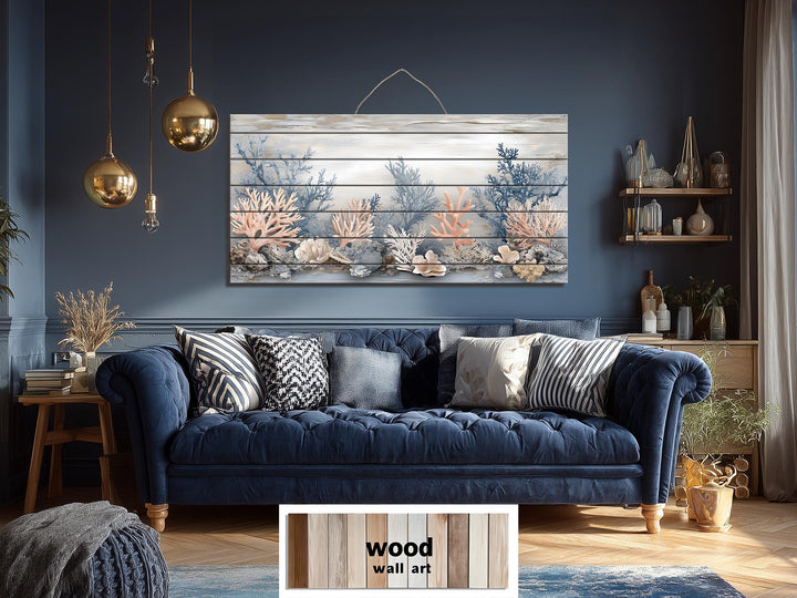 Coastal coral scene printed on a horizontal distressed wood wall art piece above a blue sofa.