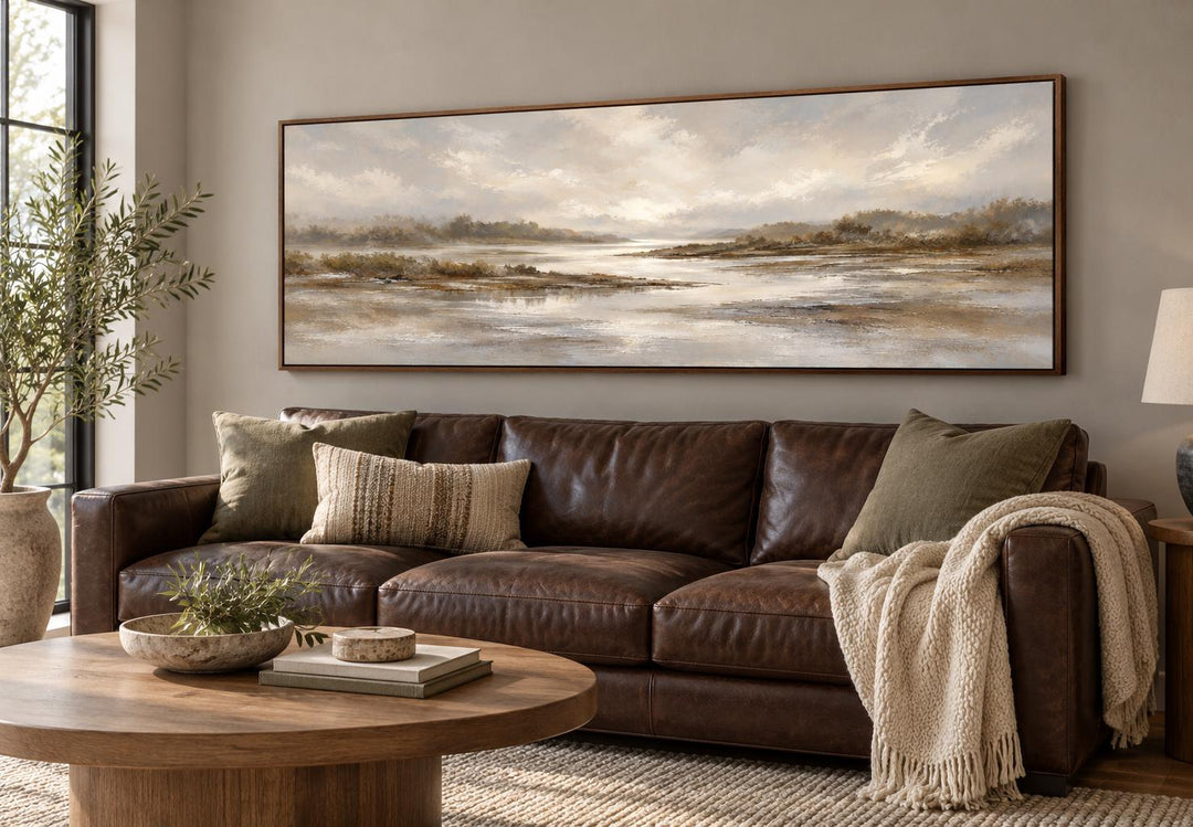 Neutral Earth Tones River Landscape Long Horizontal Canvas Wall Art above a brown leather sofa.