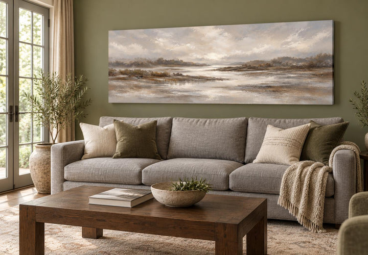 Neutral earth tones river landscape long horizontal canvas wall art above a gray sofa.