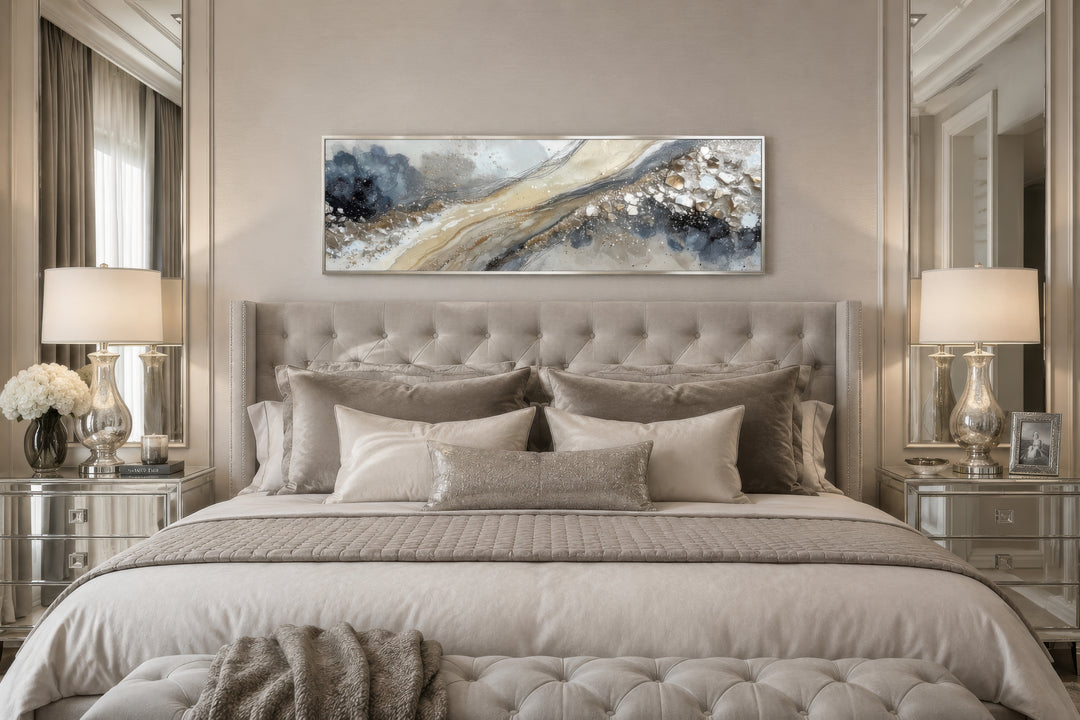 Neutral grey, beige, and gold horizontal abstract canvas wall art hanging above a tufted bed.