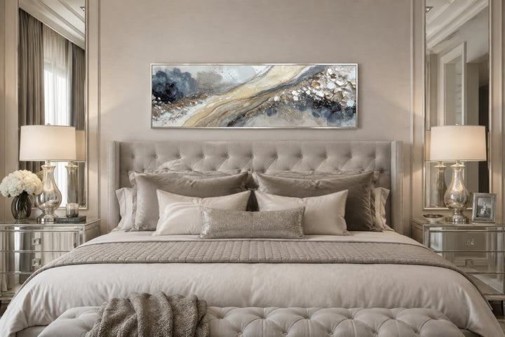 Neutral grey, beige, and gold horizontal abstract canvas wall art hanging above a tufted bed.