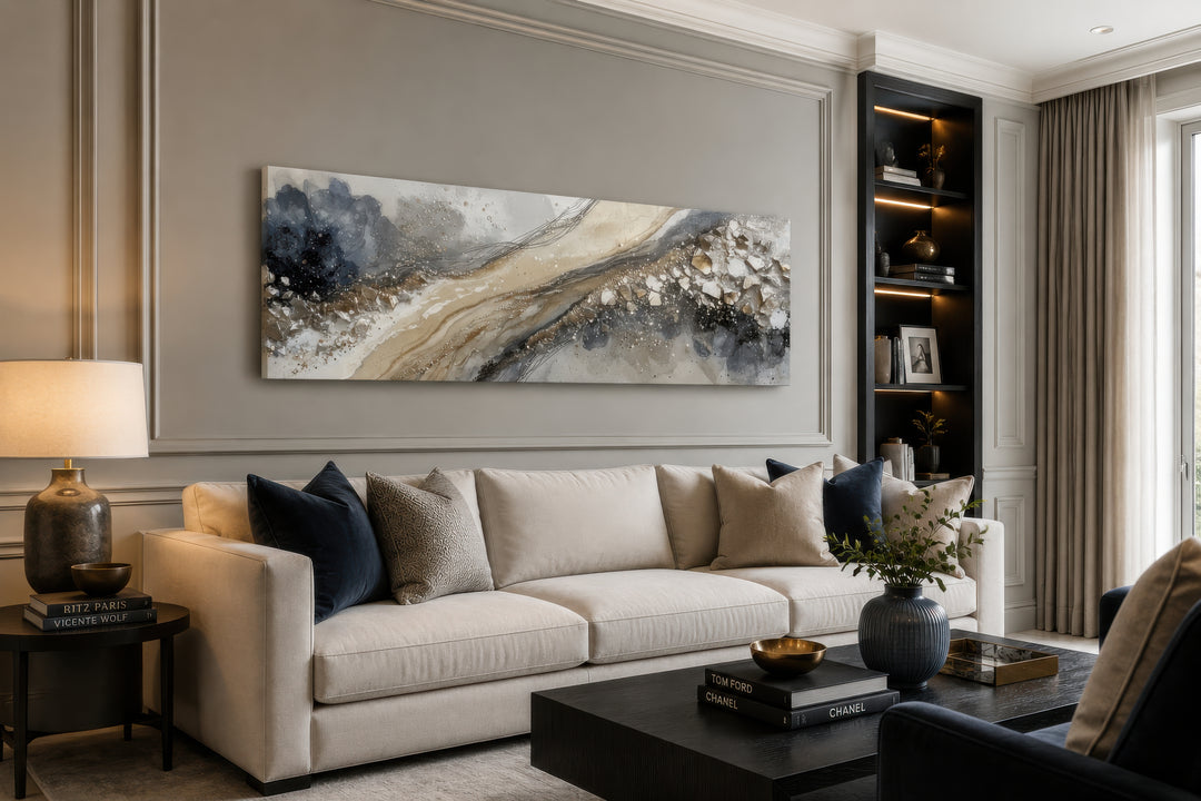 Long horizontal abstract canvas wall art in neutral grey, beige, and gold above a cream sofa.