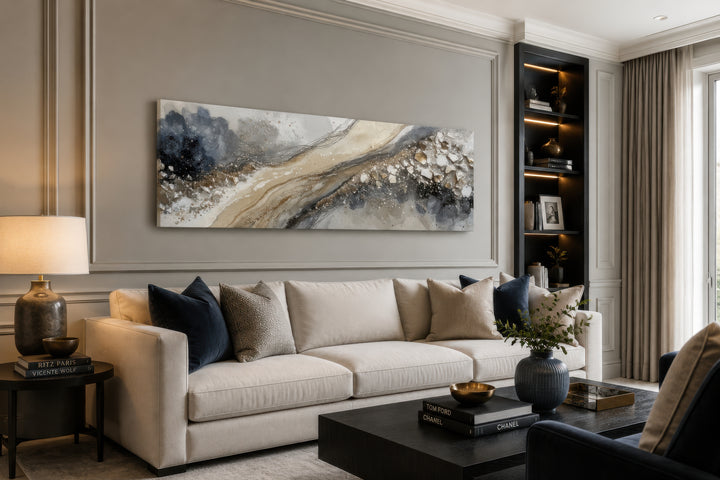 Long horizontal abstract canvas wall art in neutral grey, beige, and gold above a cream sofa.