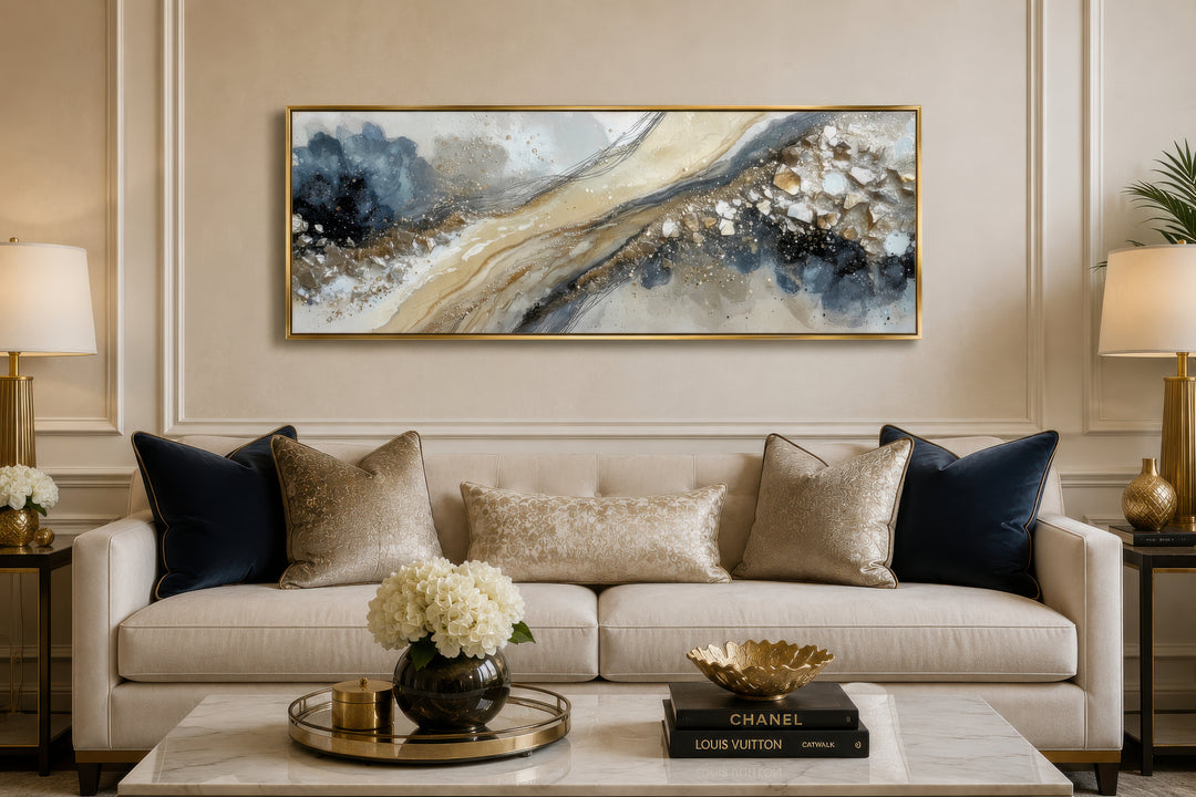 Neutral grey, beige, and gold horizontal abstract canvas wall art in a gold frame above a sofa.