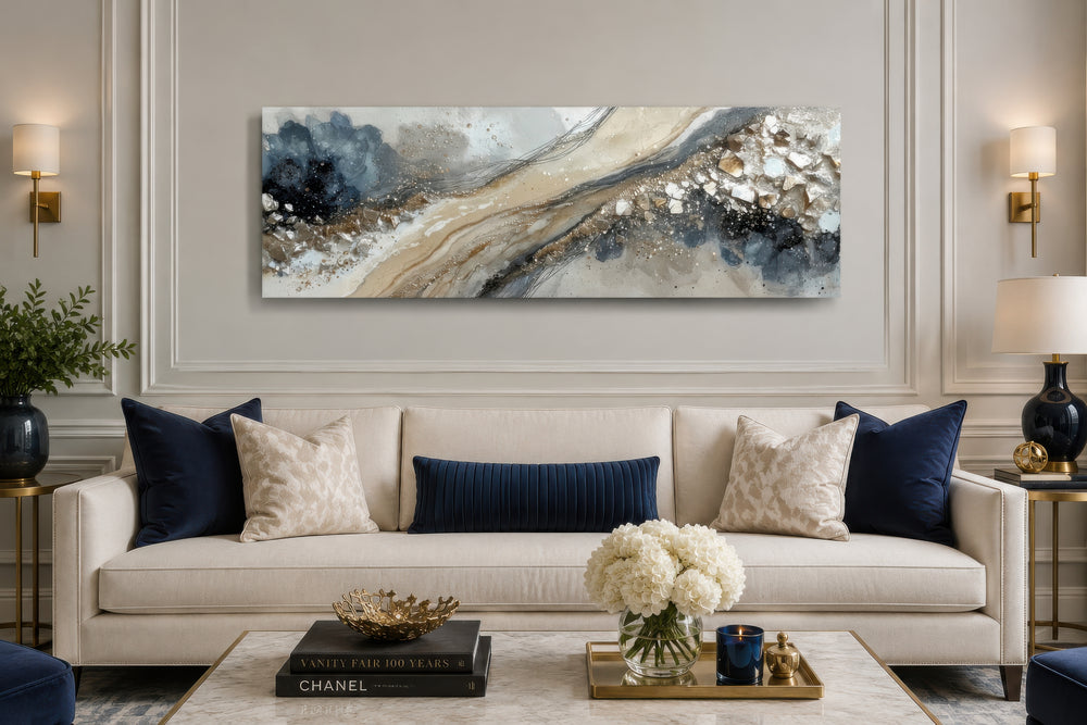 Long horizontal abstract canvas wall art in neutral grey, beige, and gold above a cream sofa.