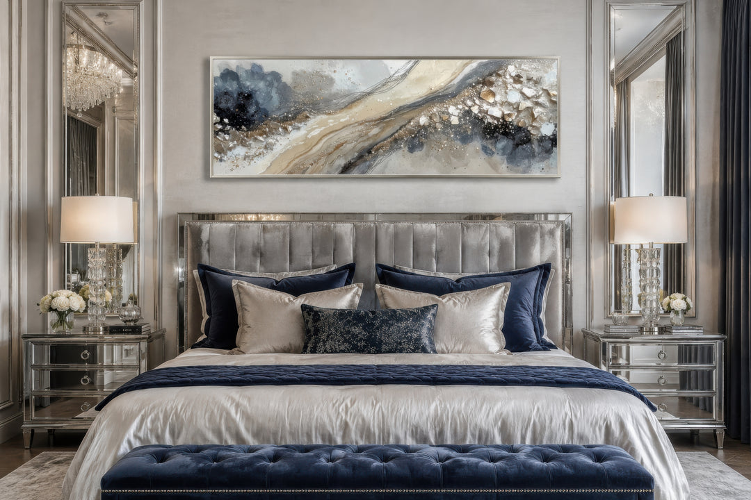 Long horizontal abstract canvas wall art in neutral grey, beige, and gold above a luxury bed.