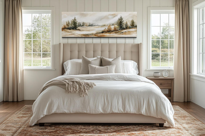 Panoramic landscape canvas art featuring beige and green trees above a neutral upholstered bed.