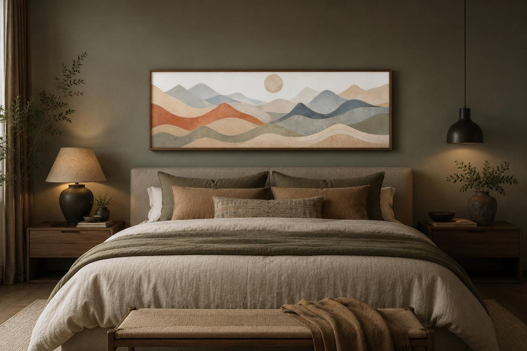 Long horizontal panoramic canvas of layered mountains in neutral tones hanging above a bed.