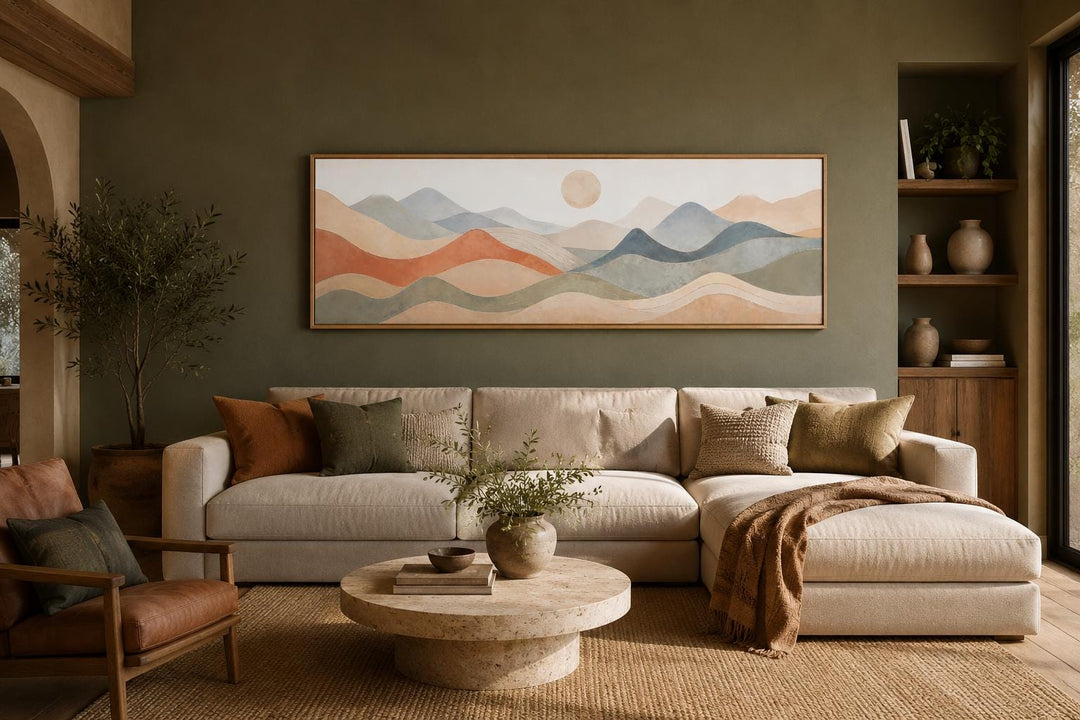 Long horizontal panoramic canvas art of layered mountains in neutral tones above a beige sofa.