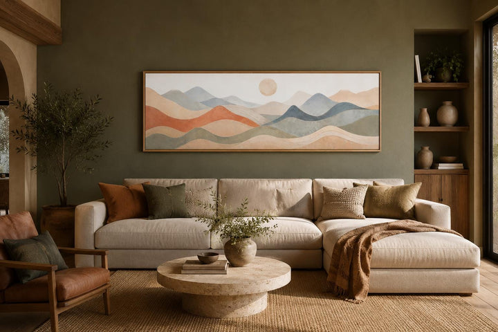 Long horizontal panoramic canvas art of layered mountains in neutral tones above a beige sofa.