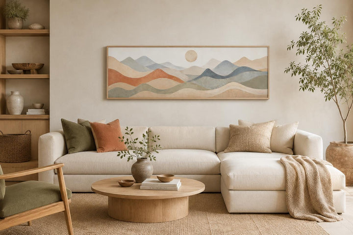 Neutral layered mountain landscape panoramic canvas art above a cream sofa in a modern living room.