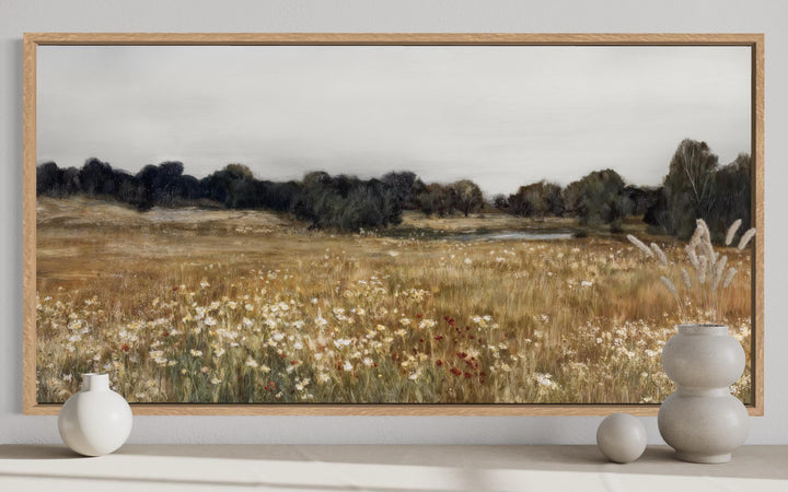 Neutral wildflower field landscape canvas wall art in a wood frame above a console table.