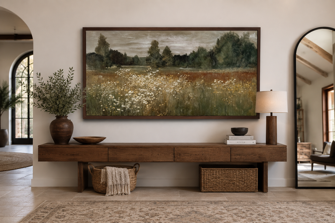 Neutral wildflower meadow wall art in a dark wood frame above a long wooden console table.