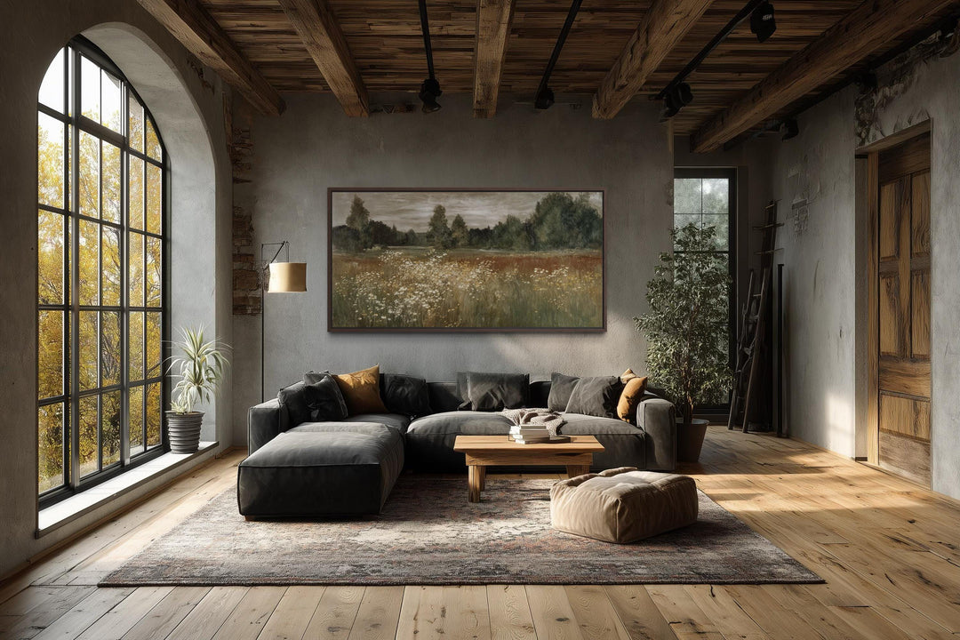 Neutral wildflower meadow canvas wall art in a rustic farmhouse living room above a dark sofa.