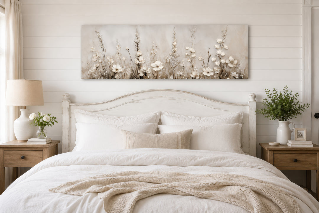Neutral wildflower canvas print in beige and cream tones hanging above a white wooden bed frame.