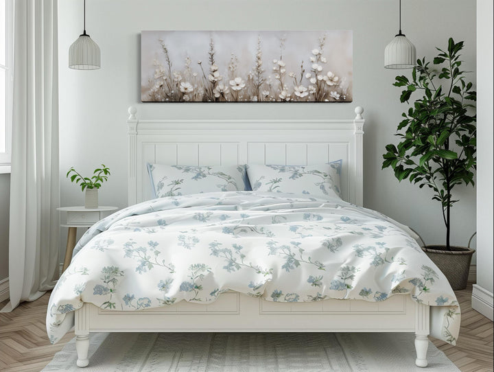 Neutral wildflower canvas wall art in beige and ivory tones hanging above a white wooden bed.
