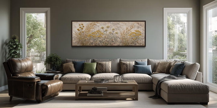 A long narrow canvas print of neutral wildflowers and meadow grass hangs above a modern sofa.