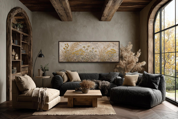 Long narrow canvas print of neutral wildflowers and meadow grasses in a rustic living room.