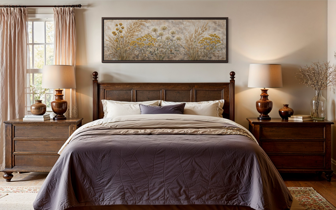A long narrow canvas print of neutral wildflowers hangs above a dark wood bed in a cozy bedroom.