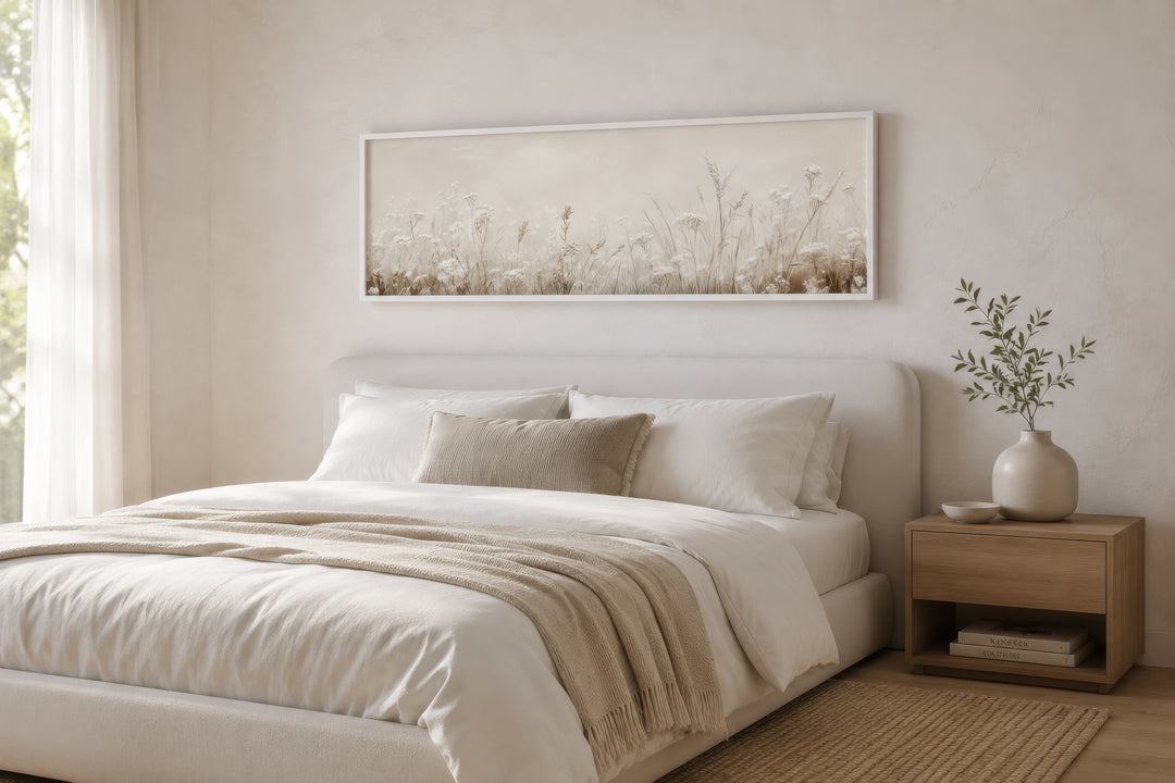 Horizontal beige wildflowers canvas print hanging above a white bed in a neutral bedroom.